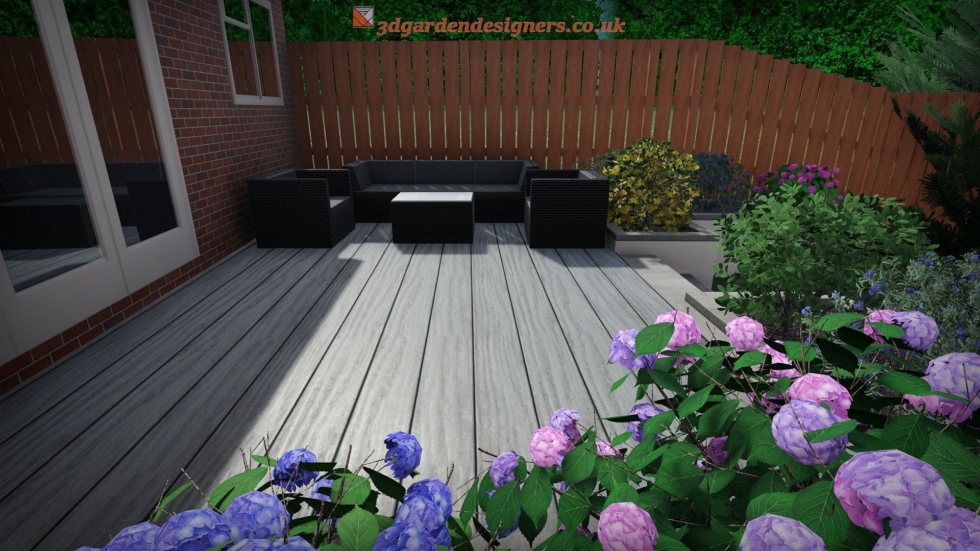 Wooden deck with black patio furniture, surrounded by flowers and greenery, in a backyard setting.