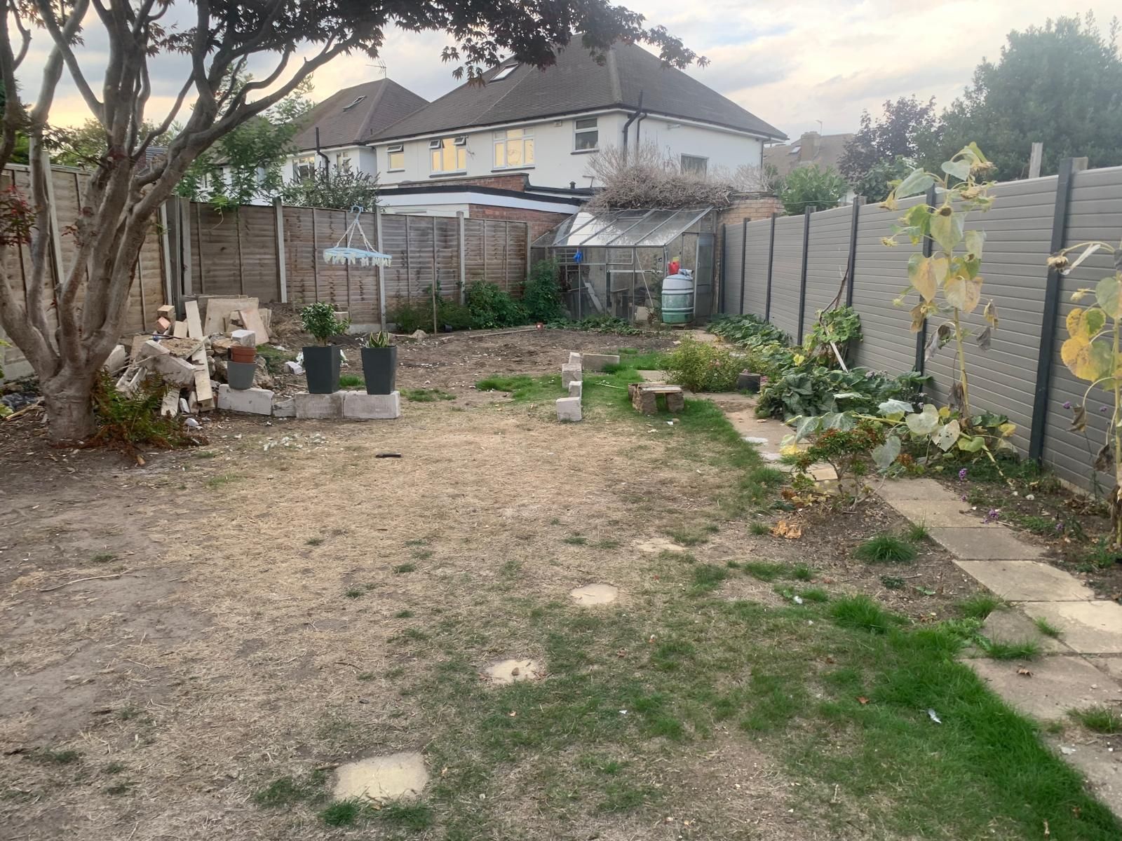 Backyard with French doors, small gravel path, gray house exterior, wooden fences, and some plants.