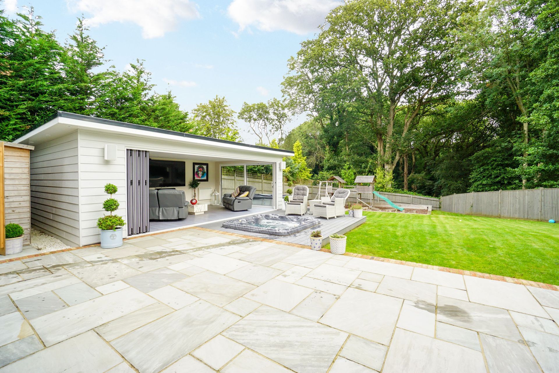 Outdoor entertainment area with a white structure, patio, and green lawn.