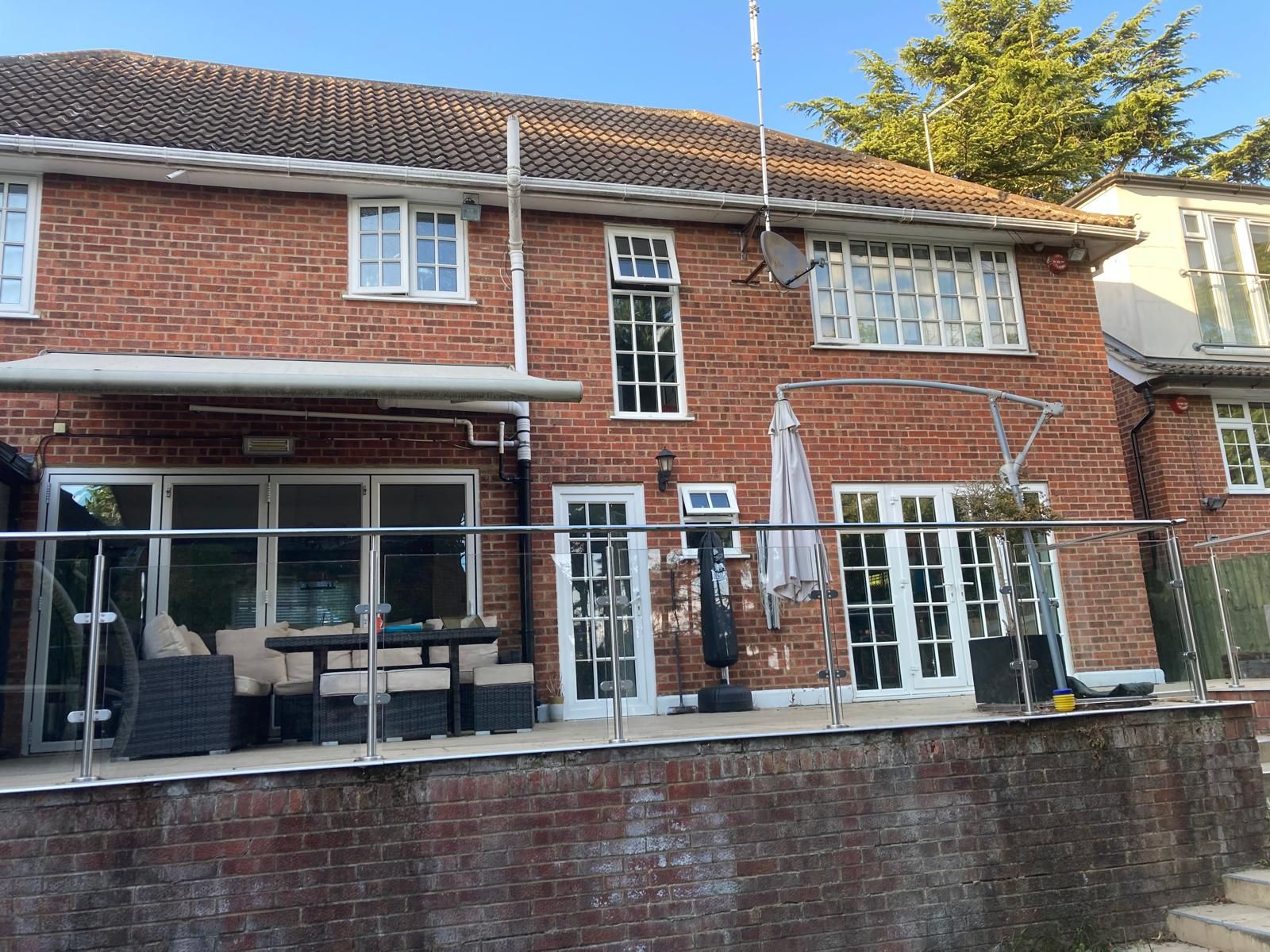 Red brick house exterior with a patio, glass doors, and a partial view of a terrace.