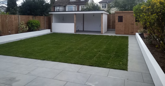 Backyard with a lawn, patio, white-painted shed, and wooden fence.