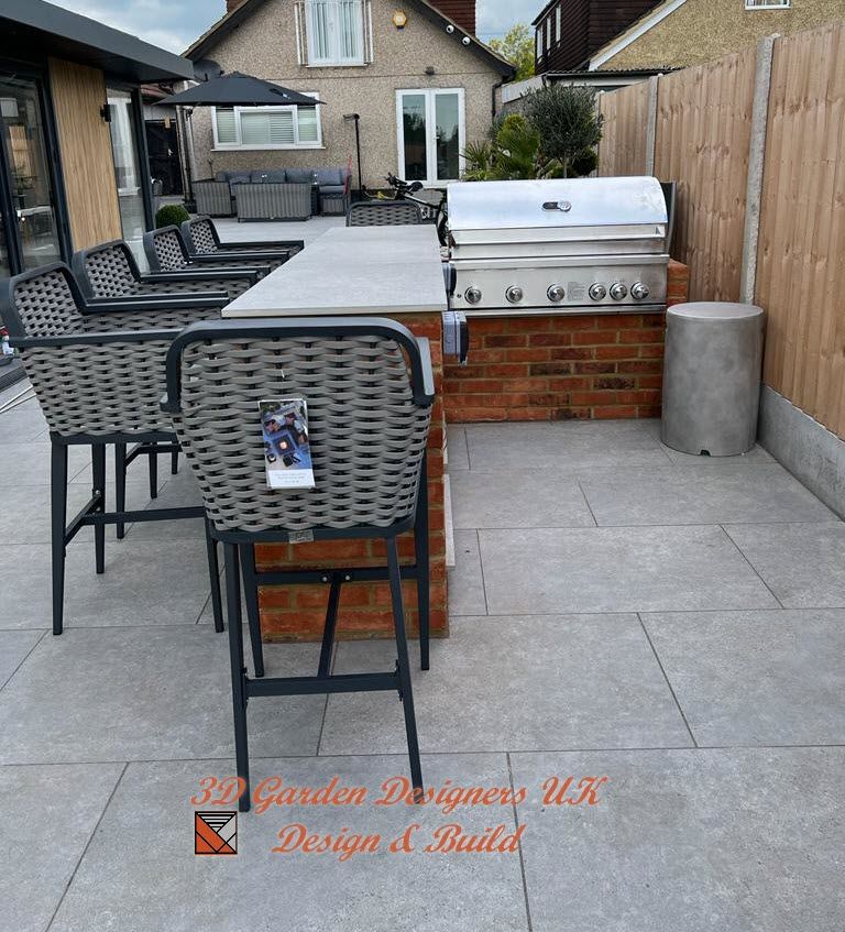 Outdoor kitchen with grill, bar seating, and gray patio. Brick base, stainless steel grill.