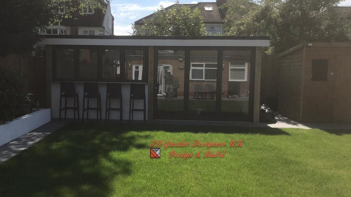 Modern garden room with bar seating, glass windows, and a shed, set in a backyard with green grass.