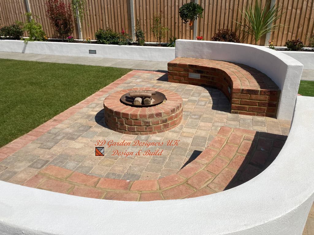 Brick patio with fire pit and curved brick bench, surrounded by white wall and lawn.