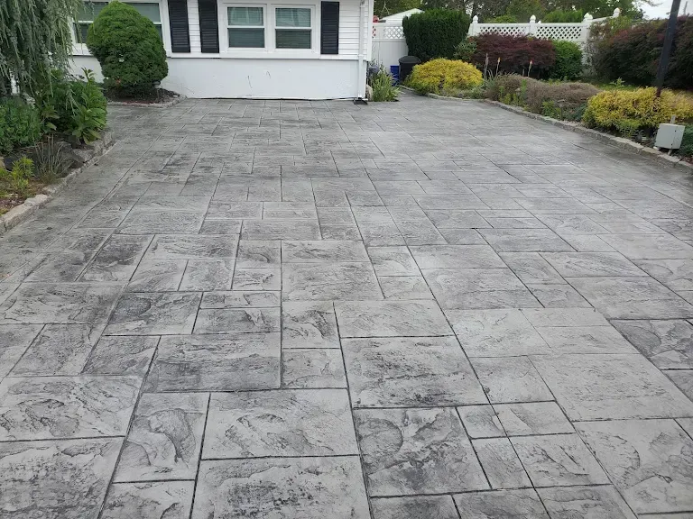 A concrete driveway with a white house in the background