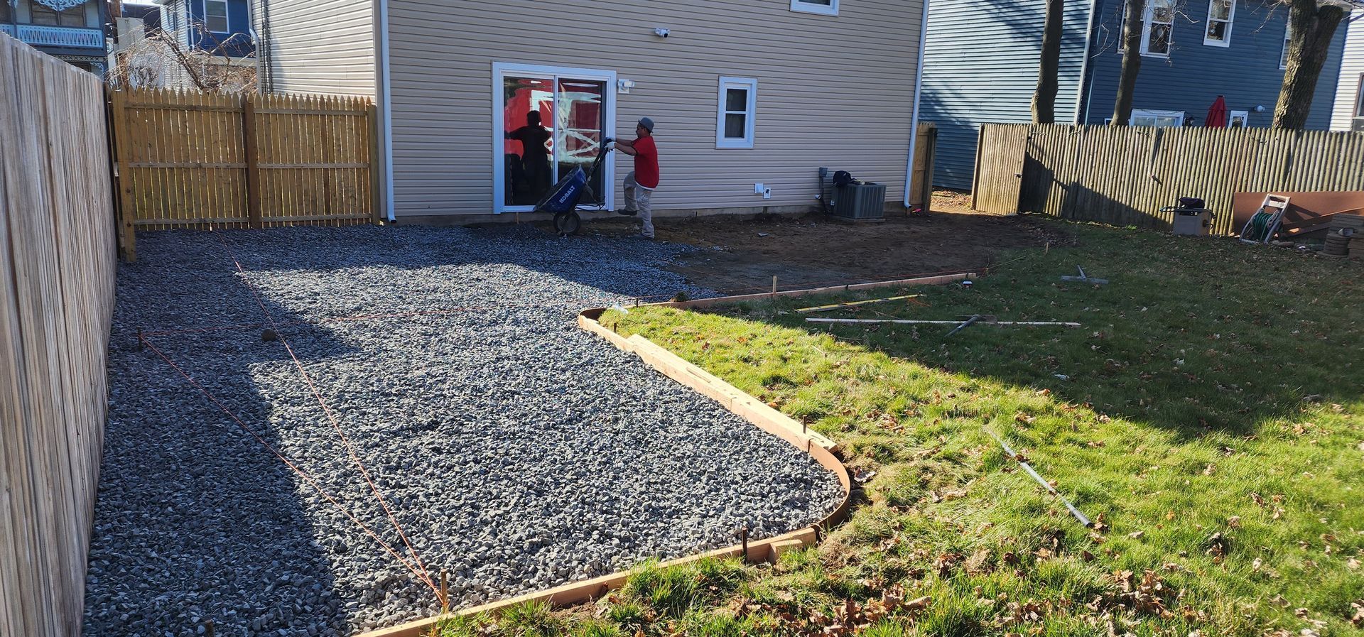 A gravel driveway is being built in front of a house.