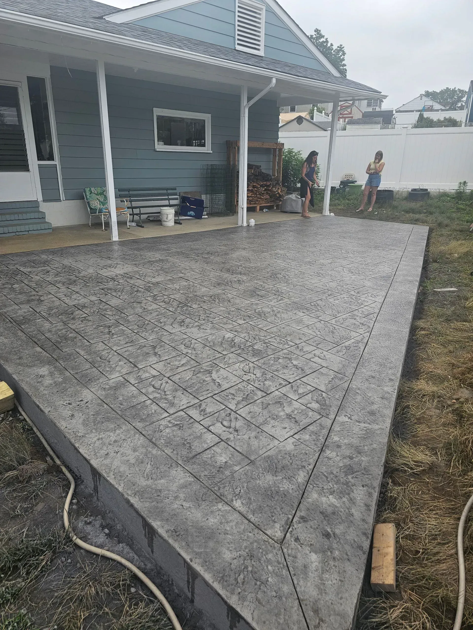 A concrete patio is being built in front of a house.