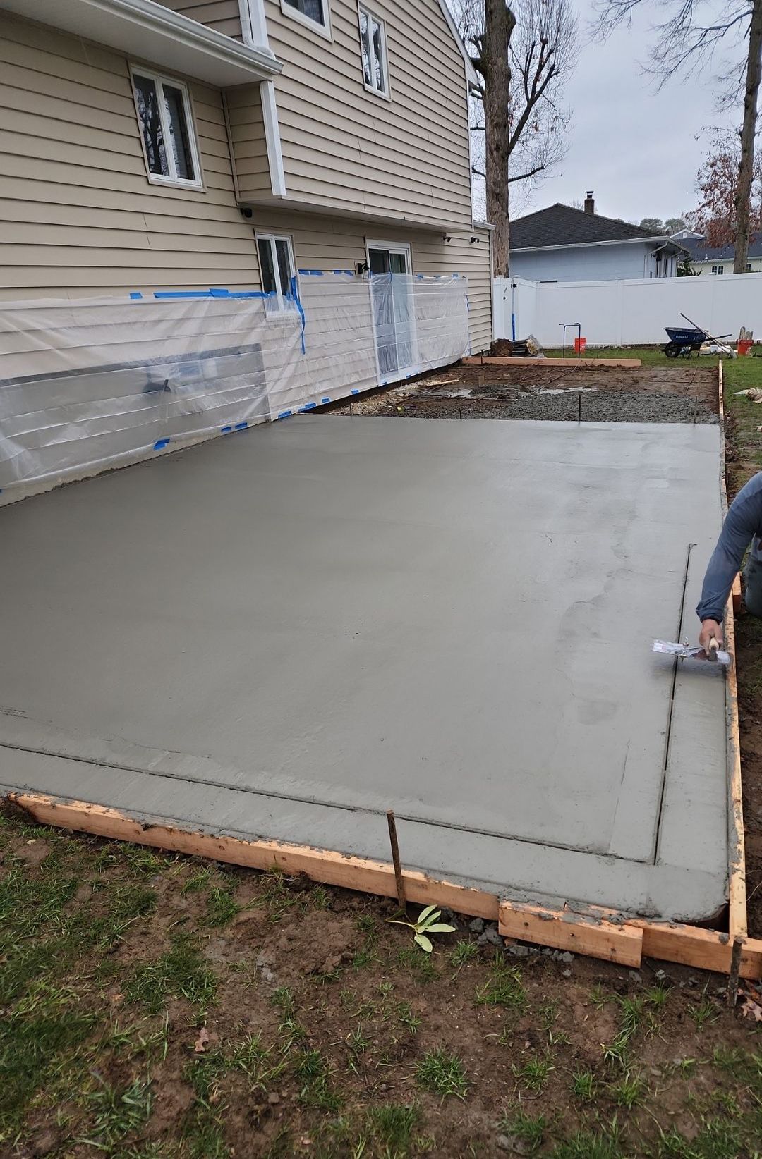 A man is working on a concrete driveway in front of a house.