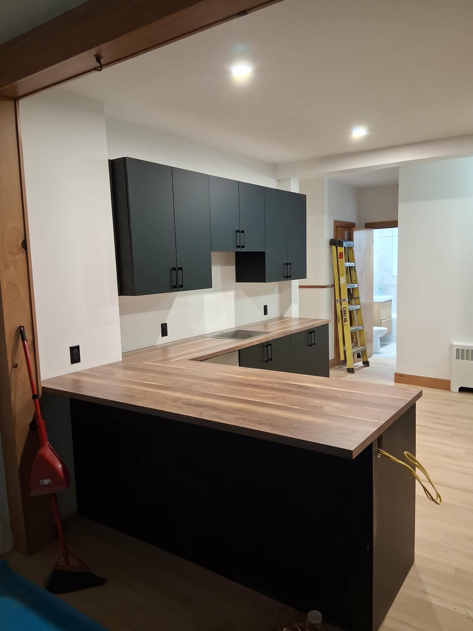 Cuisine avec placards noirs, plans de travail en bois massif et coin bar.
