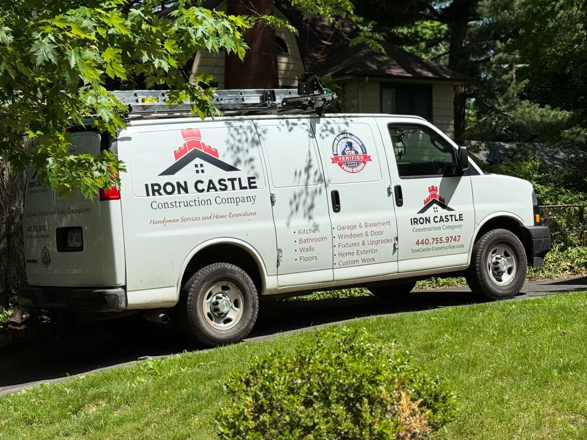White Iron Castle Construction Company van parked on a grassy verge in front of a house.