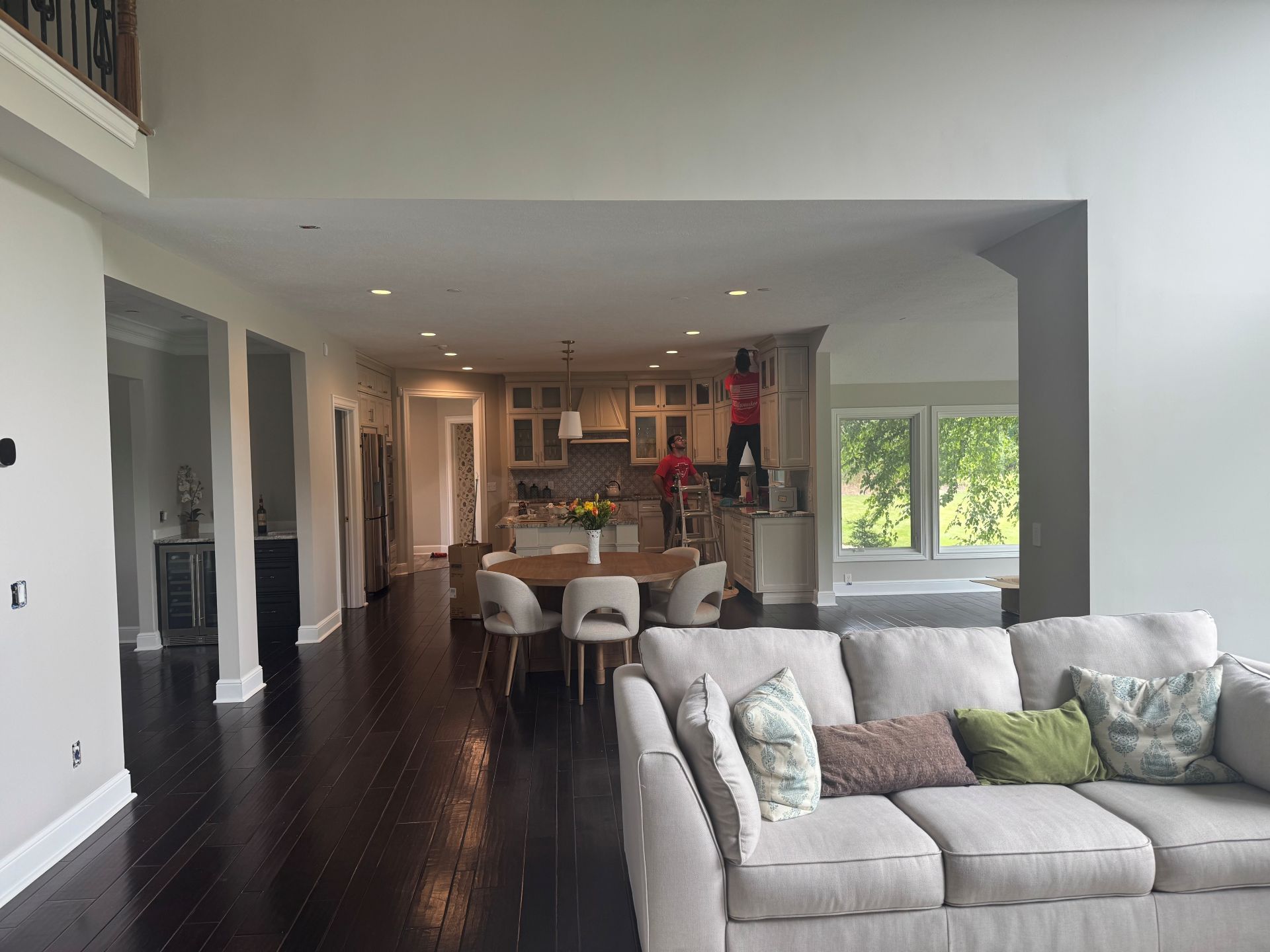 An open-concept living area with a light-colored sofa in the foreground and a dining table and kitchen in the background.