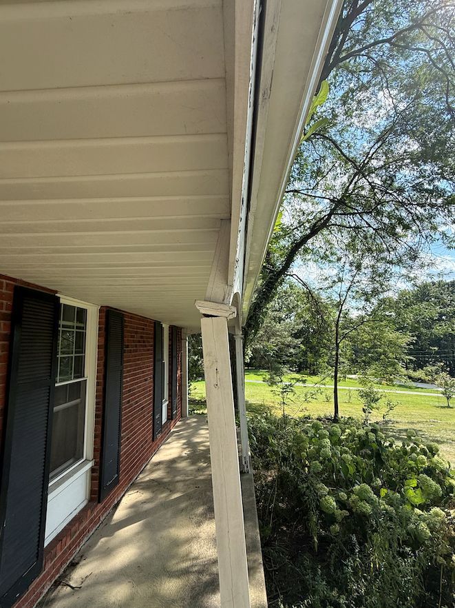 A white porch support post that has snapped and is bending outward under the weight of the roof edge.