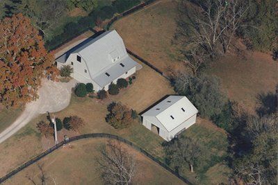 An aerial view of a house and a barn in a field