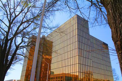 A tall building with a lot of windows is surrounded by trees.