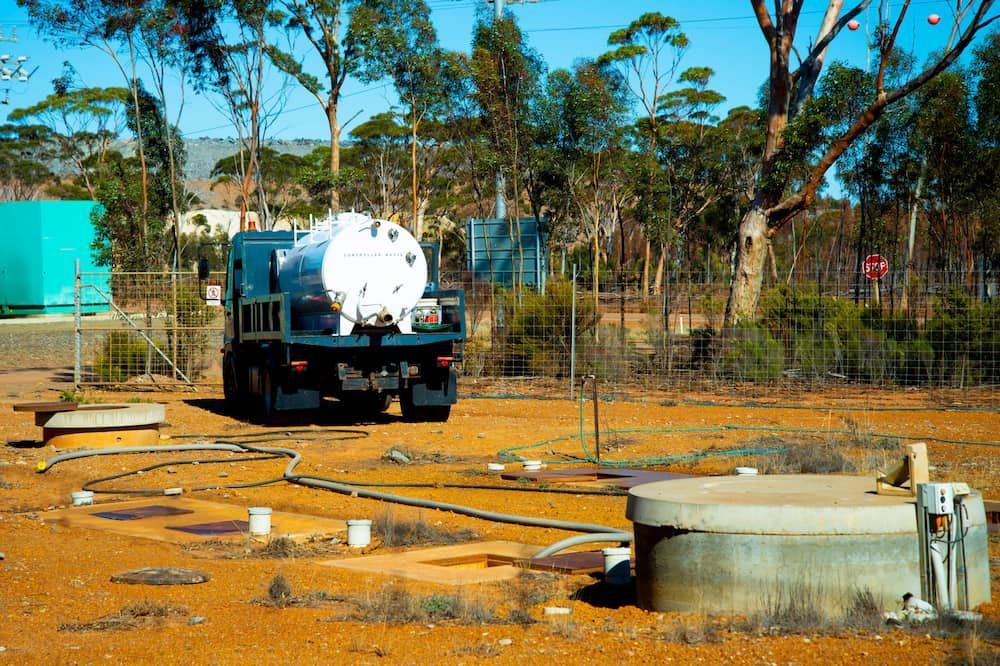 A Vacuum Truck Is Parked In A Dirt Field With Trees — ViperVac Solutions PTY LTD in Bowen, QLD