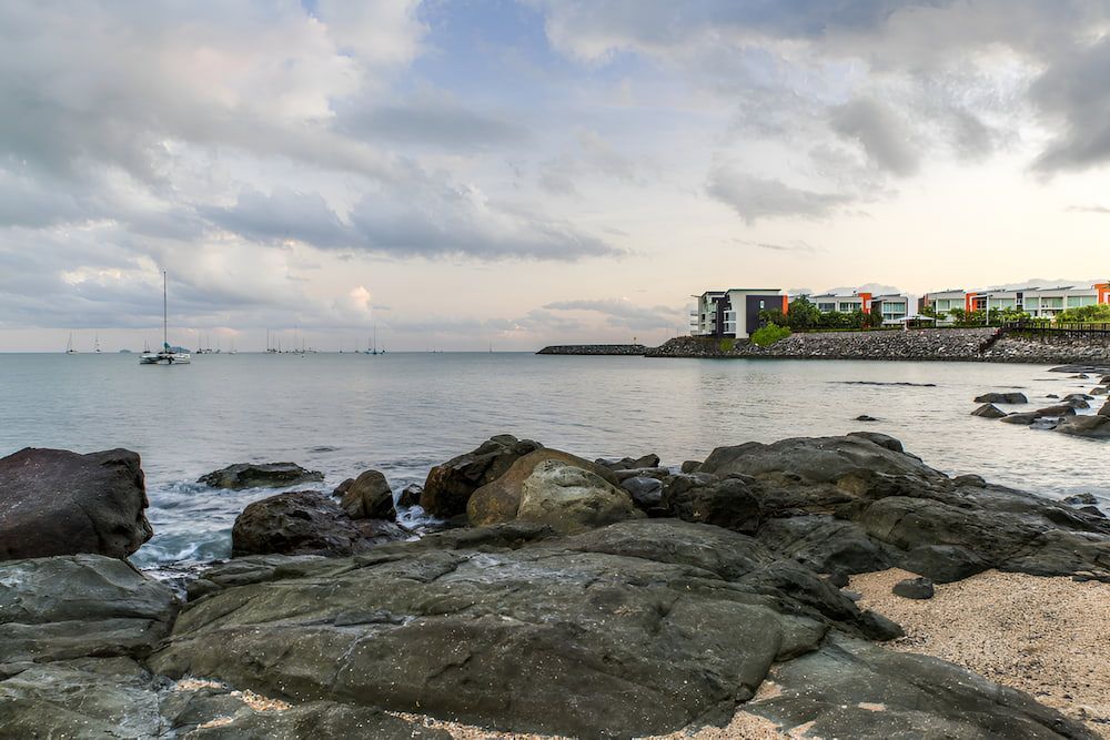 A View Of A Beach With Rocks And A Boat In The Water — ViperVac Solutions PTY LTD in Cannonvale, QLD