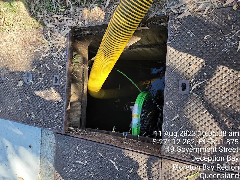 A Yellow Hose Is Being Used To Pump Water Into A Manhole Cover — ViperVac Solutions PTY LTD in Cannonvale, QLD