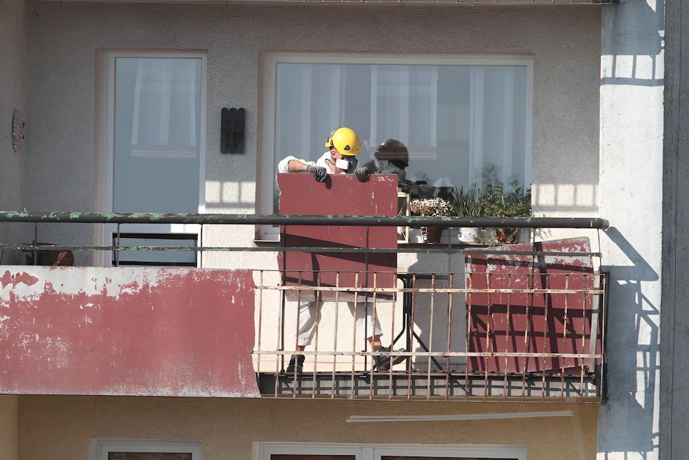 A Man Wearing A Hard Hat Is Sitting On A Balcony — ViperVac Solutions PTY LTD in Bowen, QLD