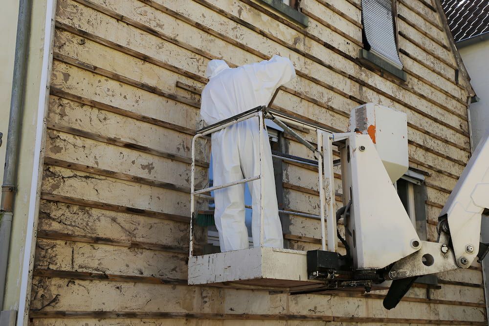 A Man In A Protective Suit Is Working On A Building — ViperVac Solutions PTY LTD in Cannonvale, QLD