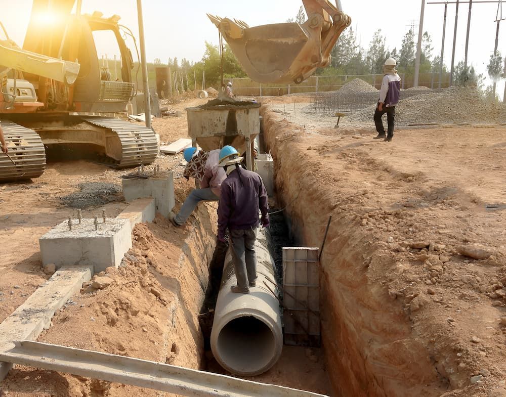 A Group Of Construction Workers Are Working On A Pipe In A Trench — ViperVac Solutions PTY LTD in Airlie Beach, QLD
