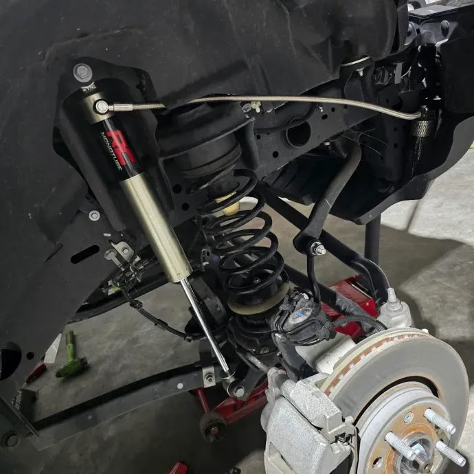Car suspension and wheel assembly with coil spring and shock absorber in a garage area