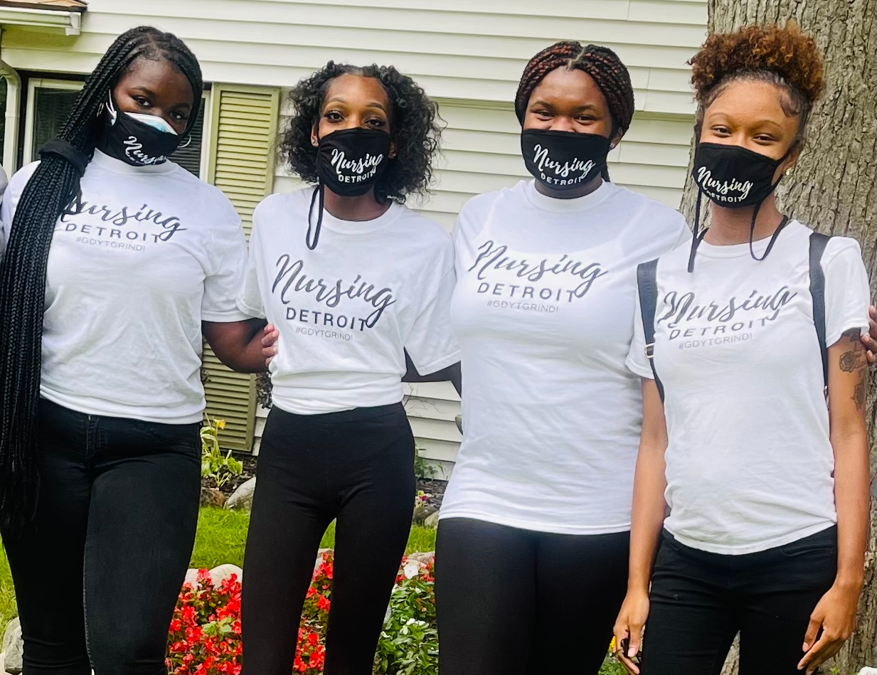 Four women wearing face masks and nursing shirts are standing next to each other.
