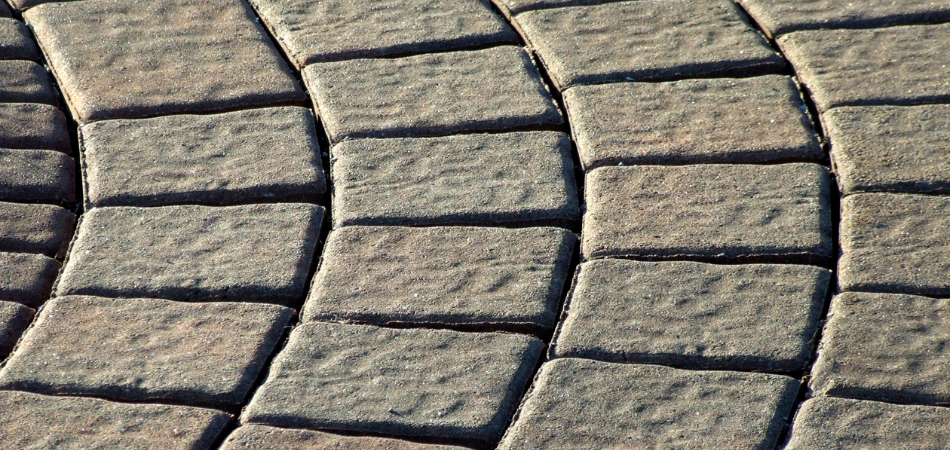 Close-up of a curved walkway made of rectangular, textured paving stones, in shades of brown and gray.