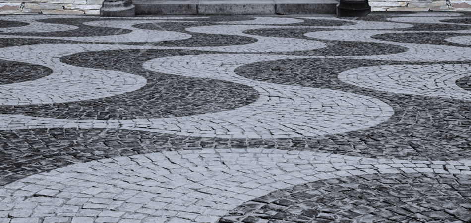 Cobblestone pavement with a black and white wave pattern.