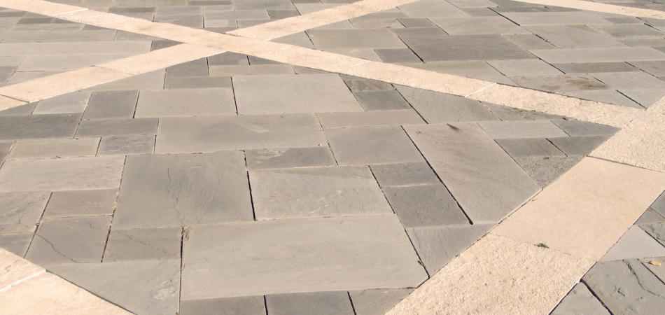 Stone pavers with light-colored grout in a crisscross pattern on a sunny day.