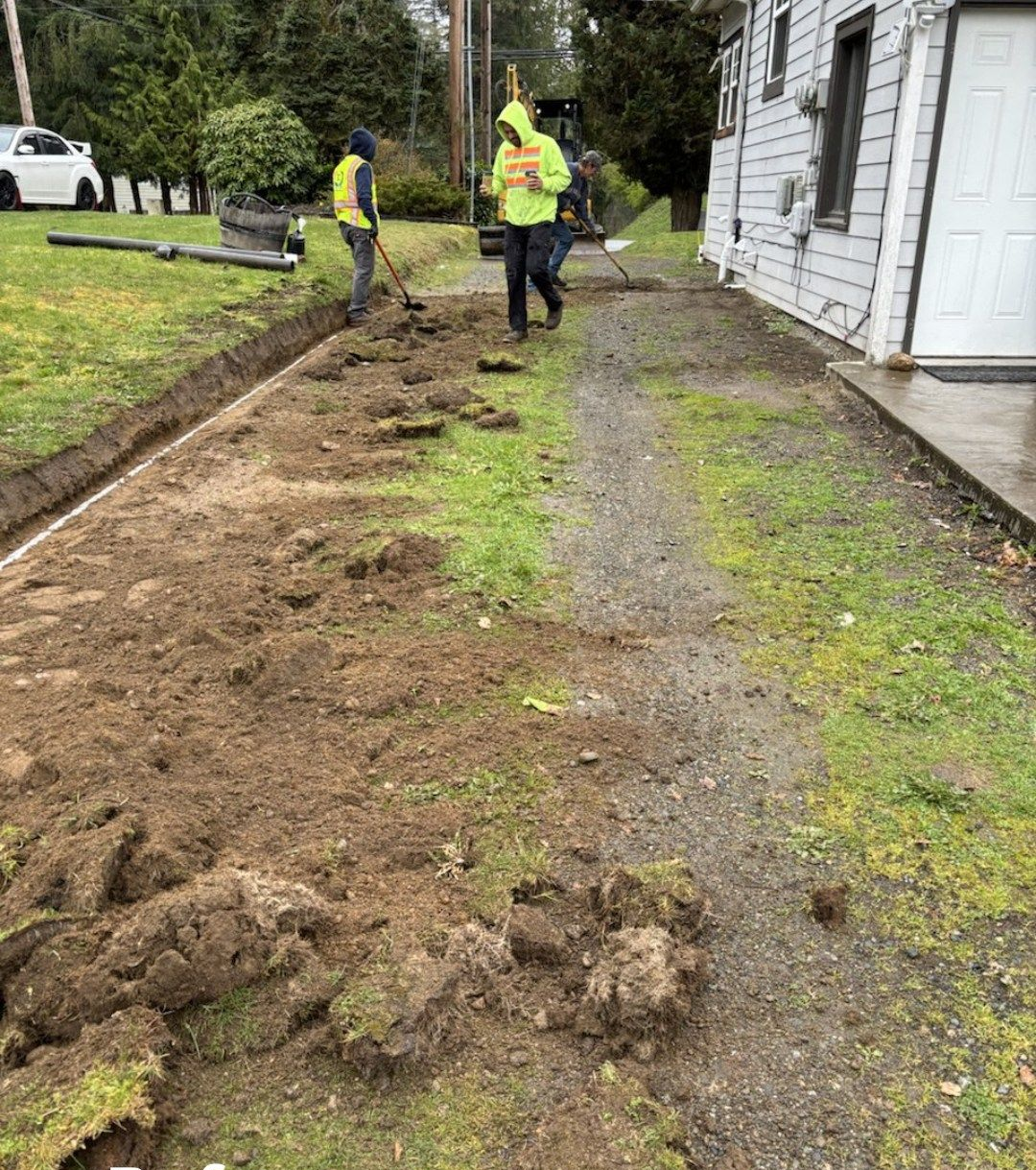 A worker finishing a newly poured concrete driveway with orange safety cone in foreground.