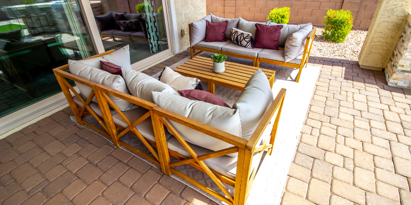 Outdoor patio with wood furniture, light cushions, and colorful throw pillows.