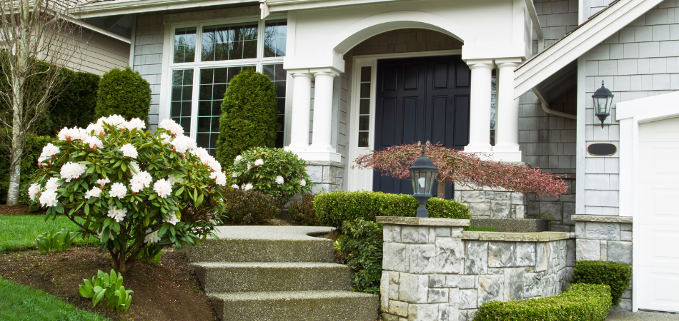 Exterior of a house with a front porch, stairs, and landscaping.