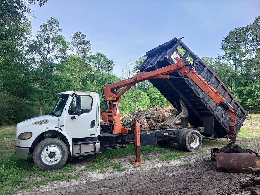 White dump truck lifting its bed at a construction site with dirt and debris nearby