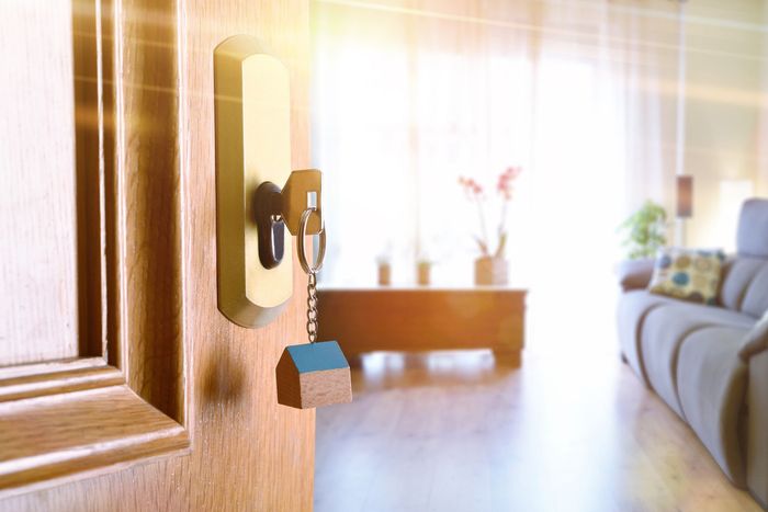 A door with a key in it is open to a living room.