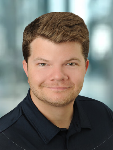 A man in a black shirt is smiling for the camera.