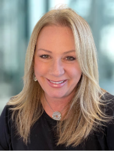 A woman wearing a black shirt and a necklace is smiling for the camera.