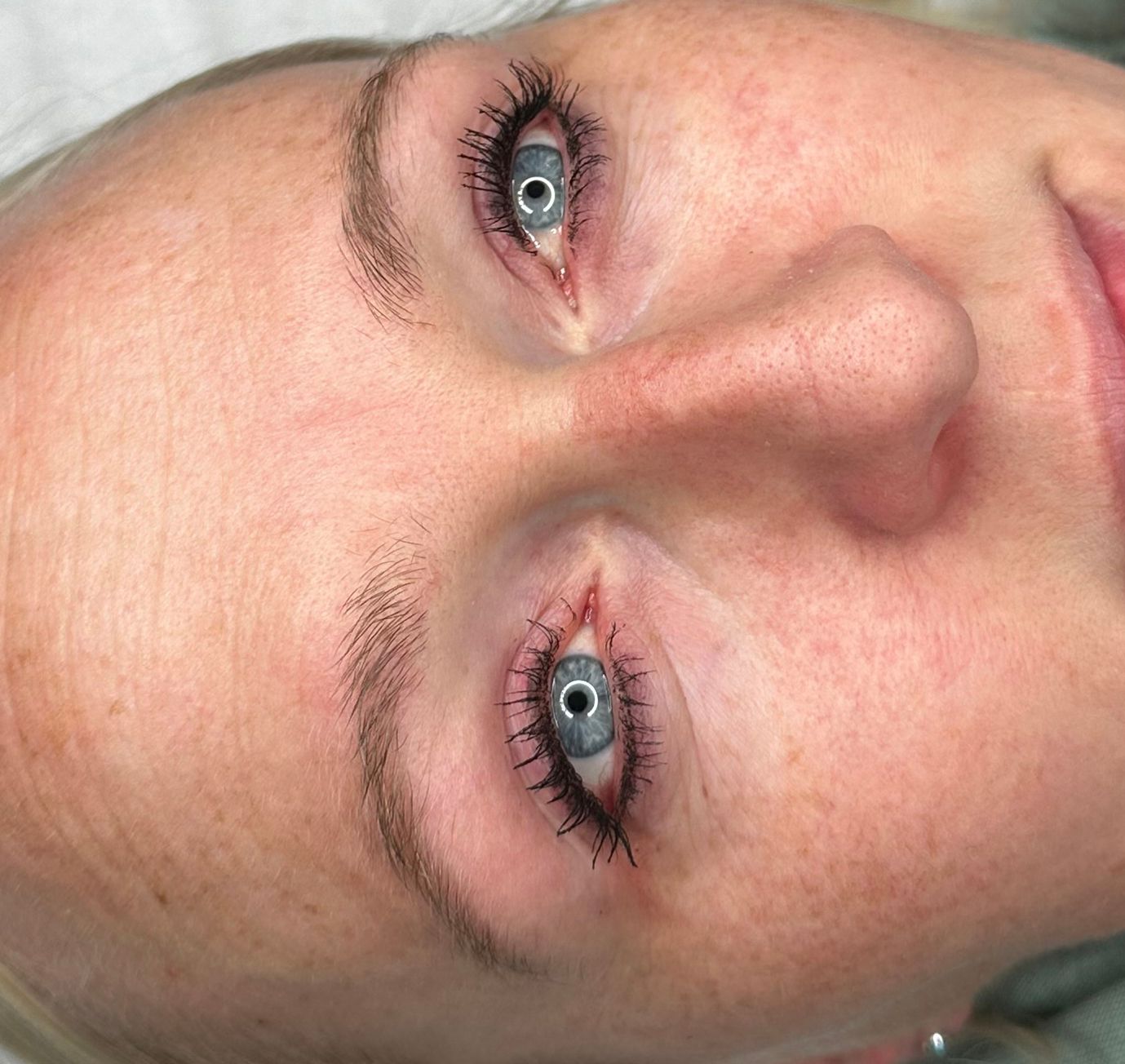 Close-up of a person's face with light skin, blue eyes, and visible mascara.