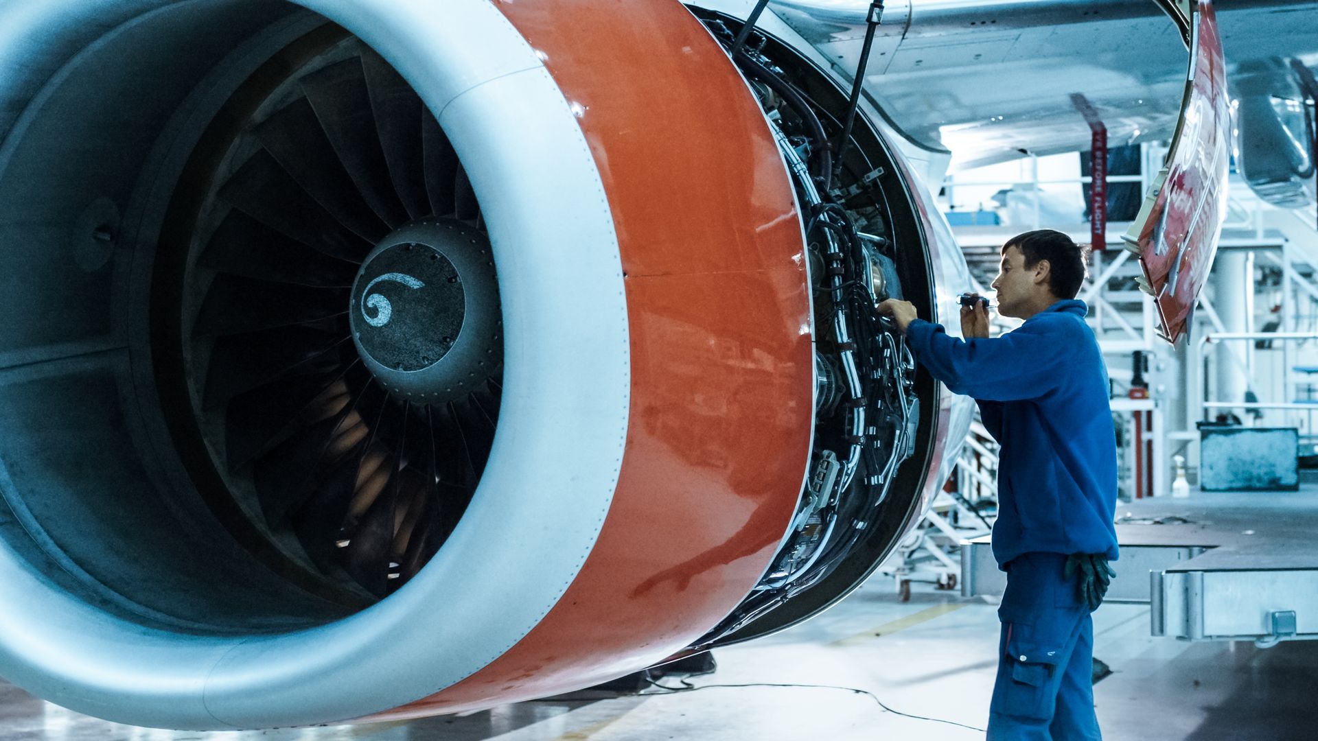 A man is working on an airplane engine in a hangar.