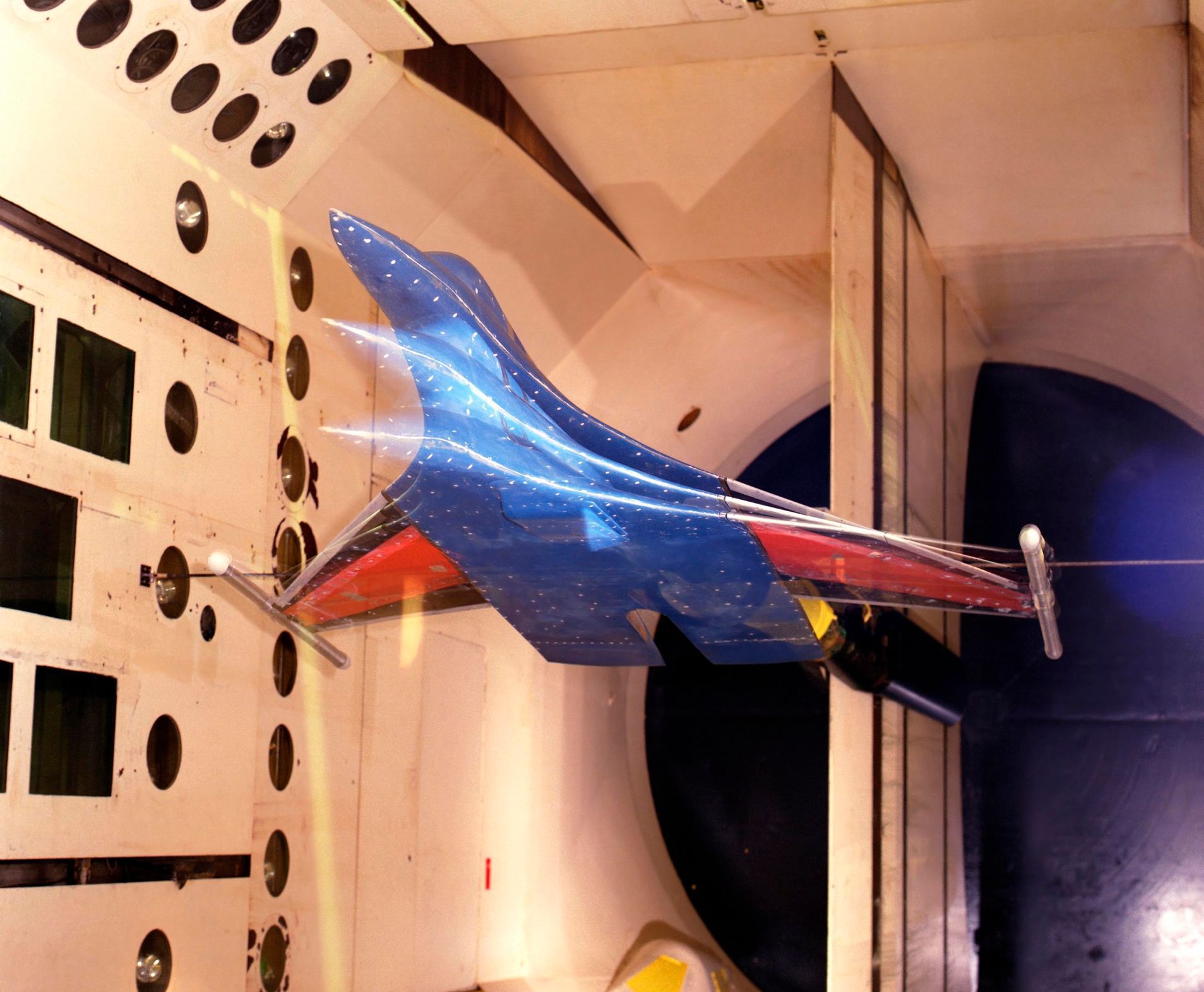 A blue and red airplane is being tested in a tunnel.