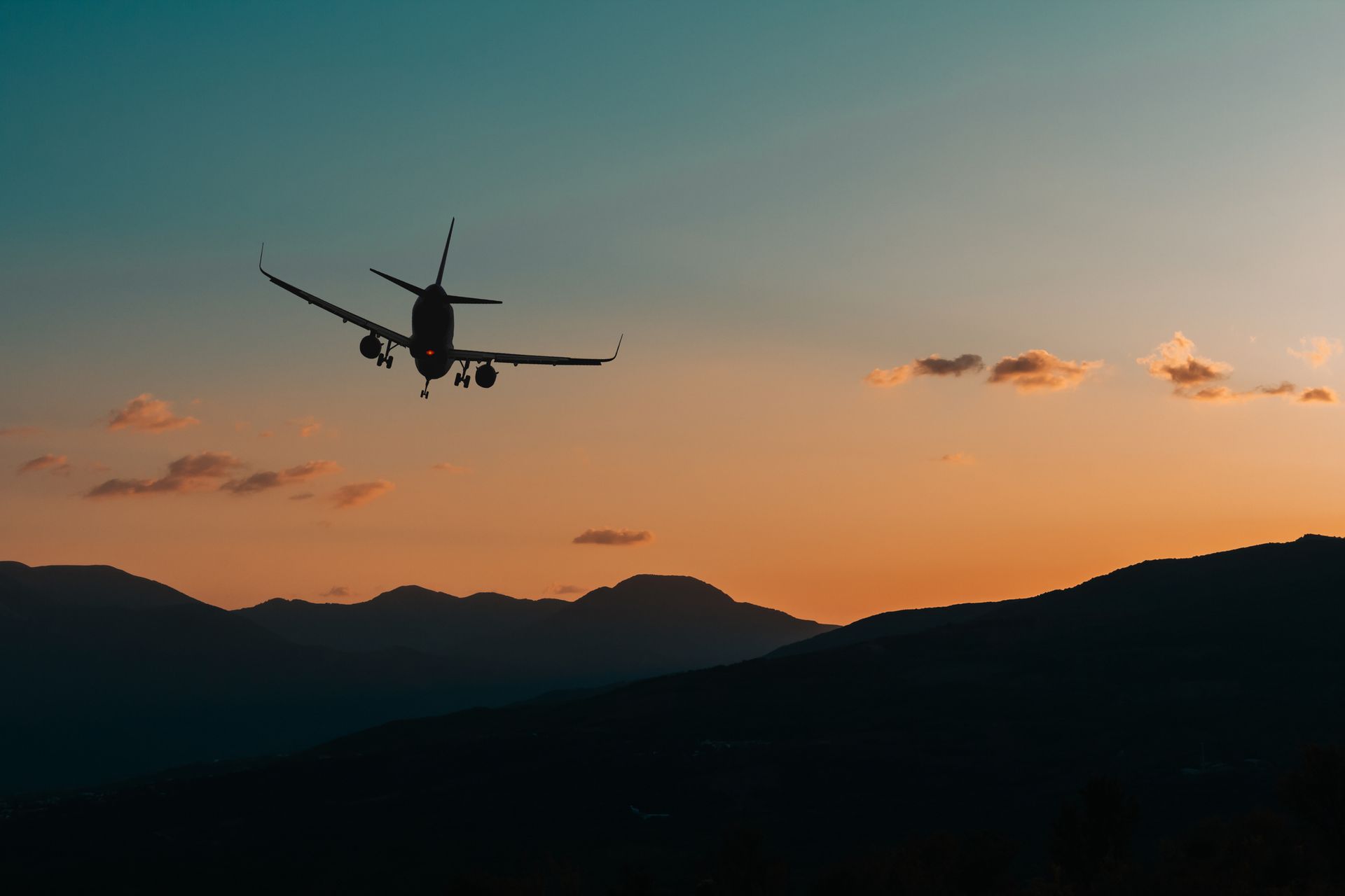 A plane is flying over a mountain range at sunset.