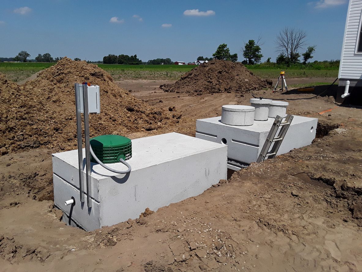 Septic tank and utility boxes installed in a dirt trench at a rural construction site