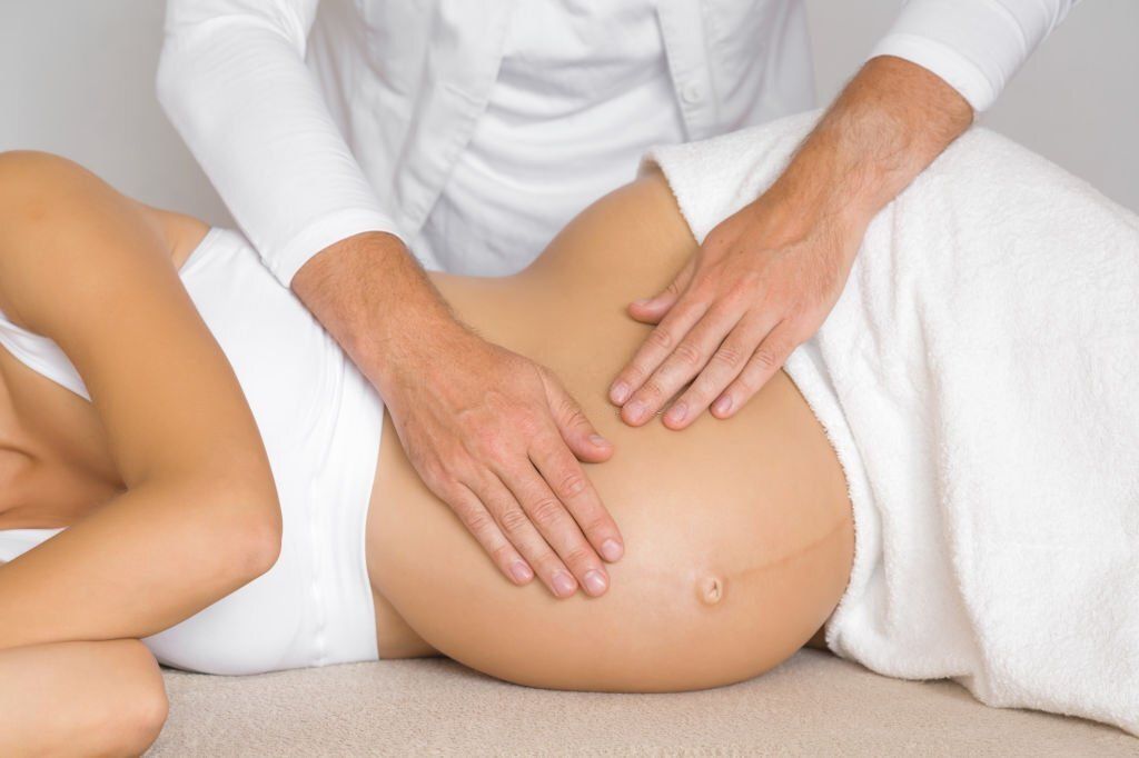 Man hands touching pregnant woman belly. Lying down on side on bed