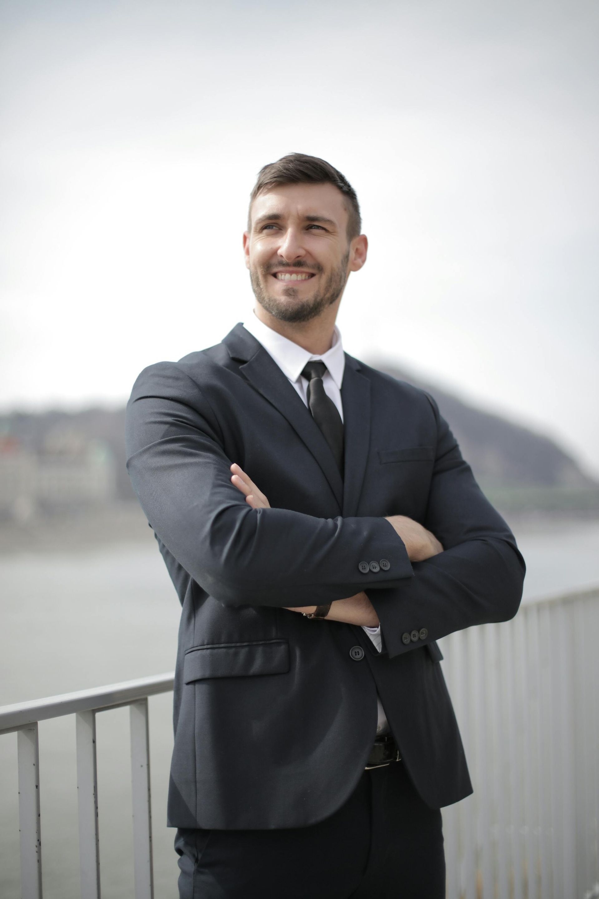 A man in a suit and tie is standing with his arms crossed.