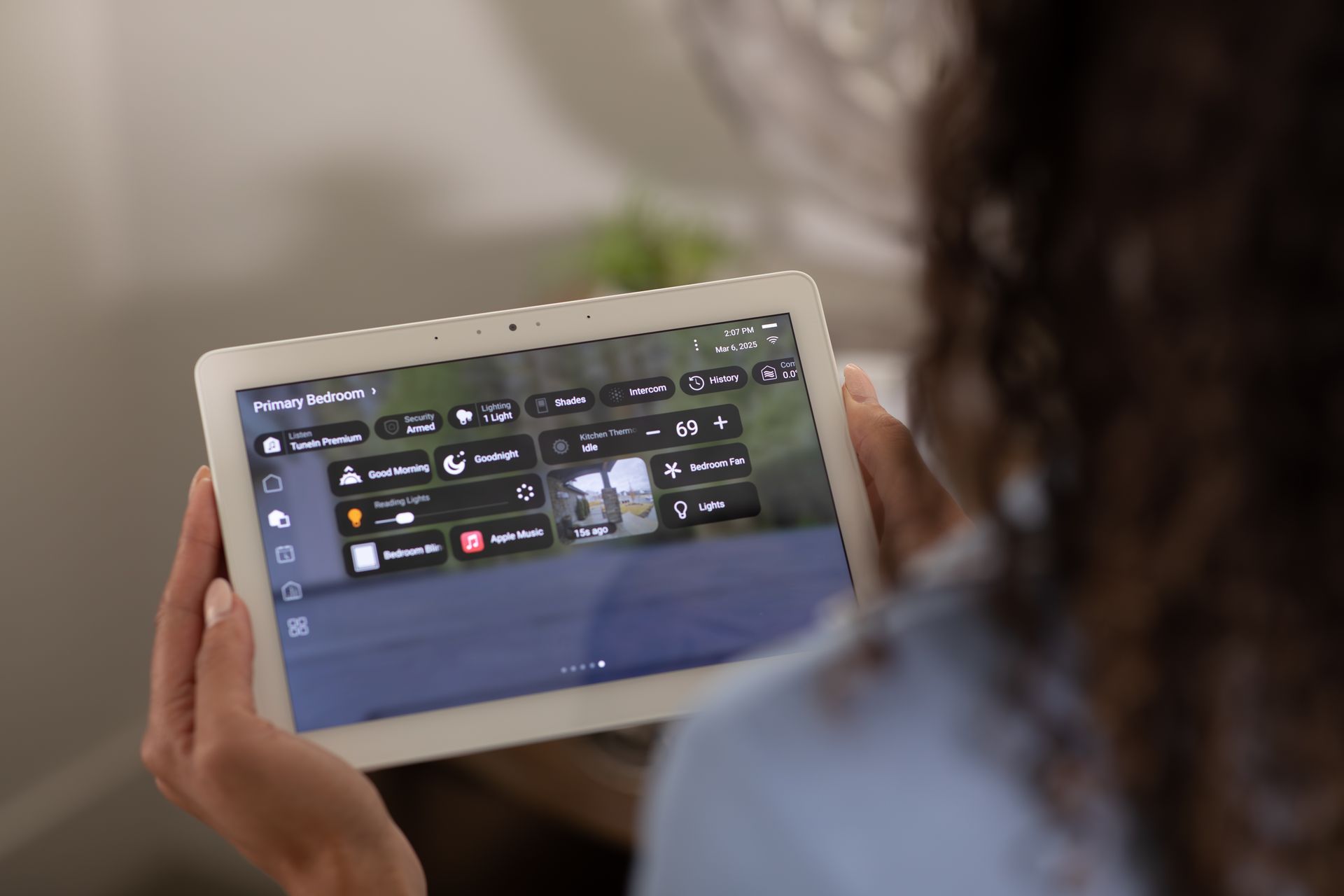 Person holding a tablet showing a dark app dashboard in a blurred indoor setting