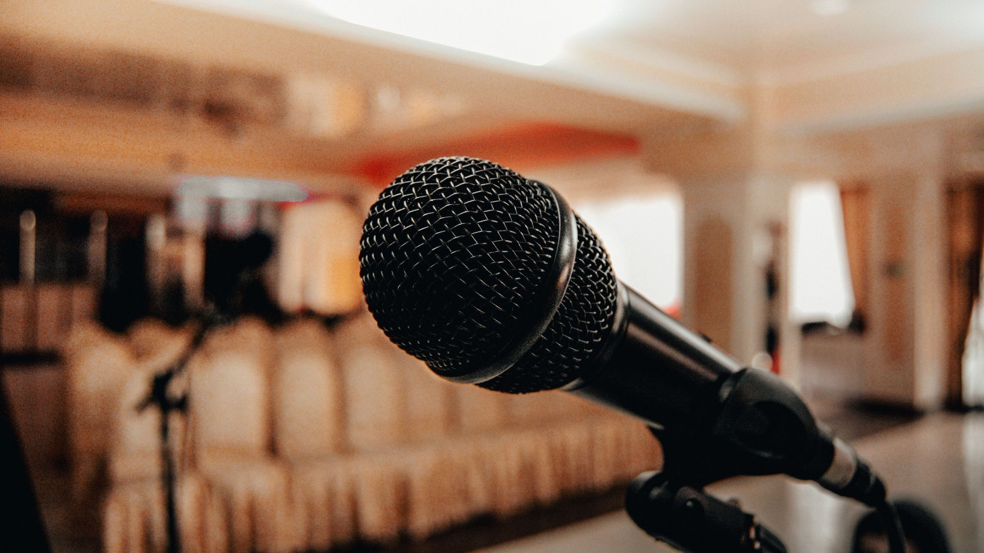 Microphone on a stand in a softly lit banquet hall with blurred tables in the background