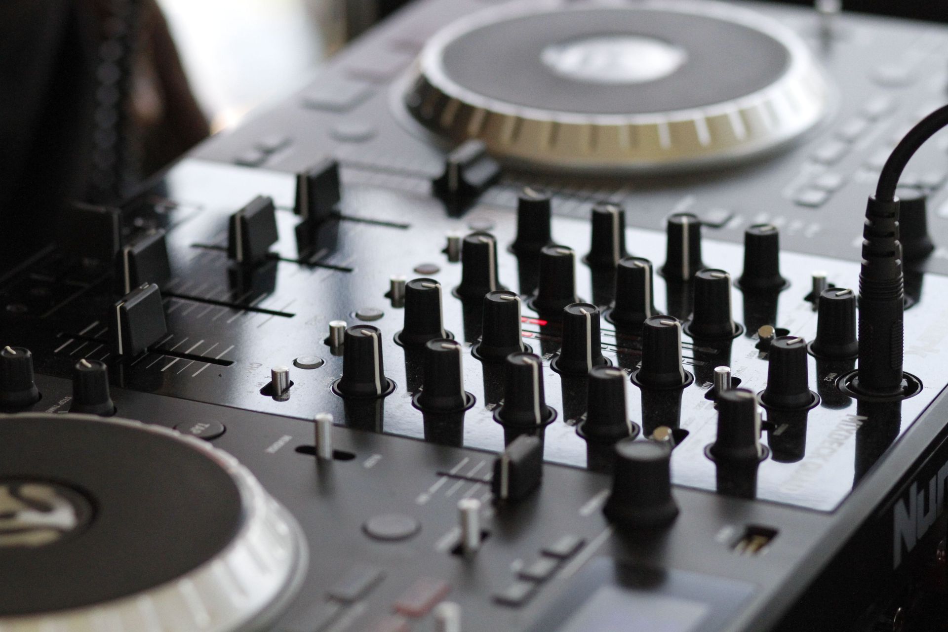 DJ mixer with turntables and rows of control knobs in a close-up view