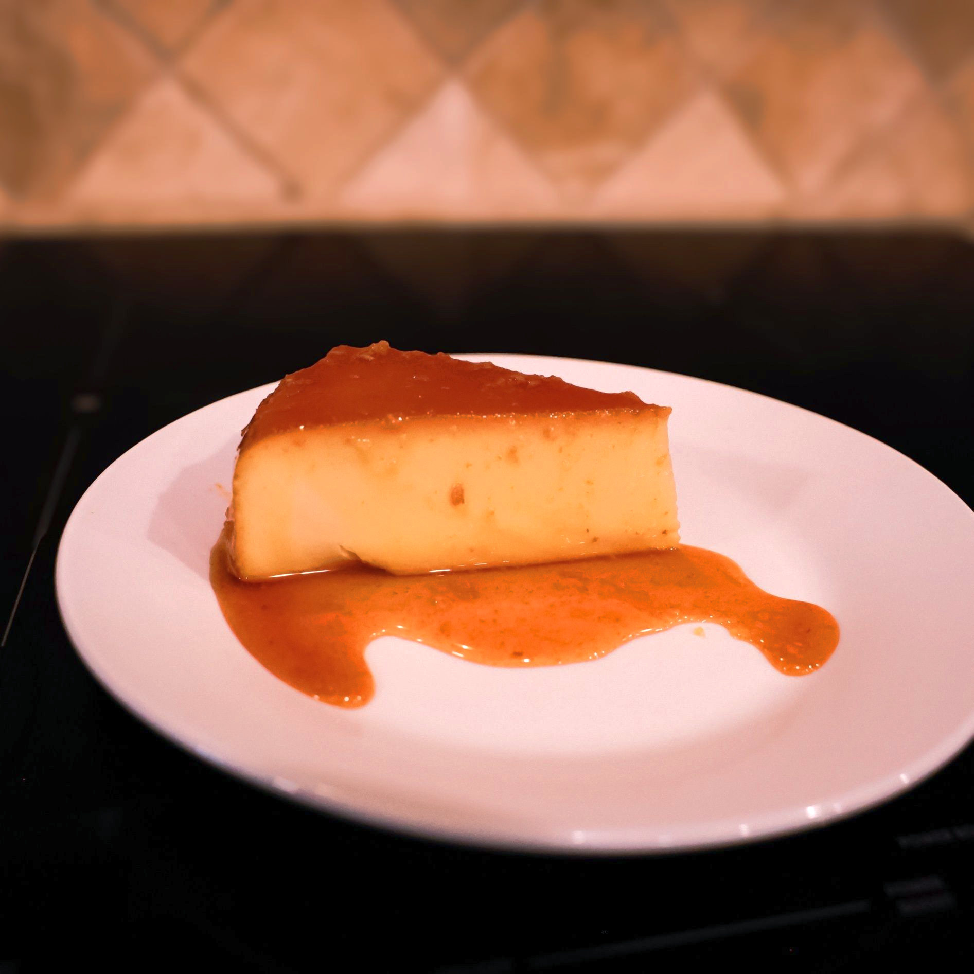 Slice of Prima AZ cream cheese flan with caramel on a white plate