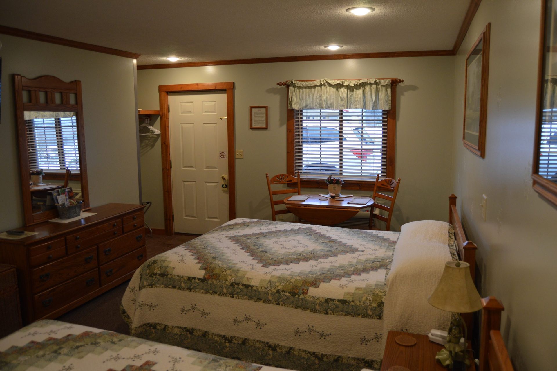 Bedroom with a bed, dresser, window seat, and beige walls with wood trim