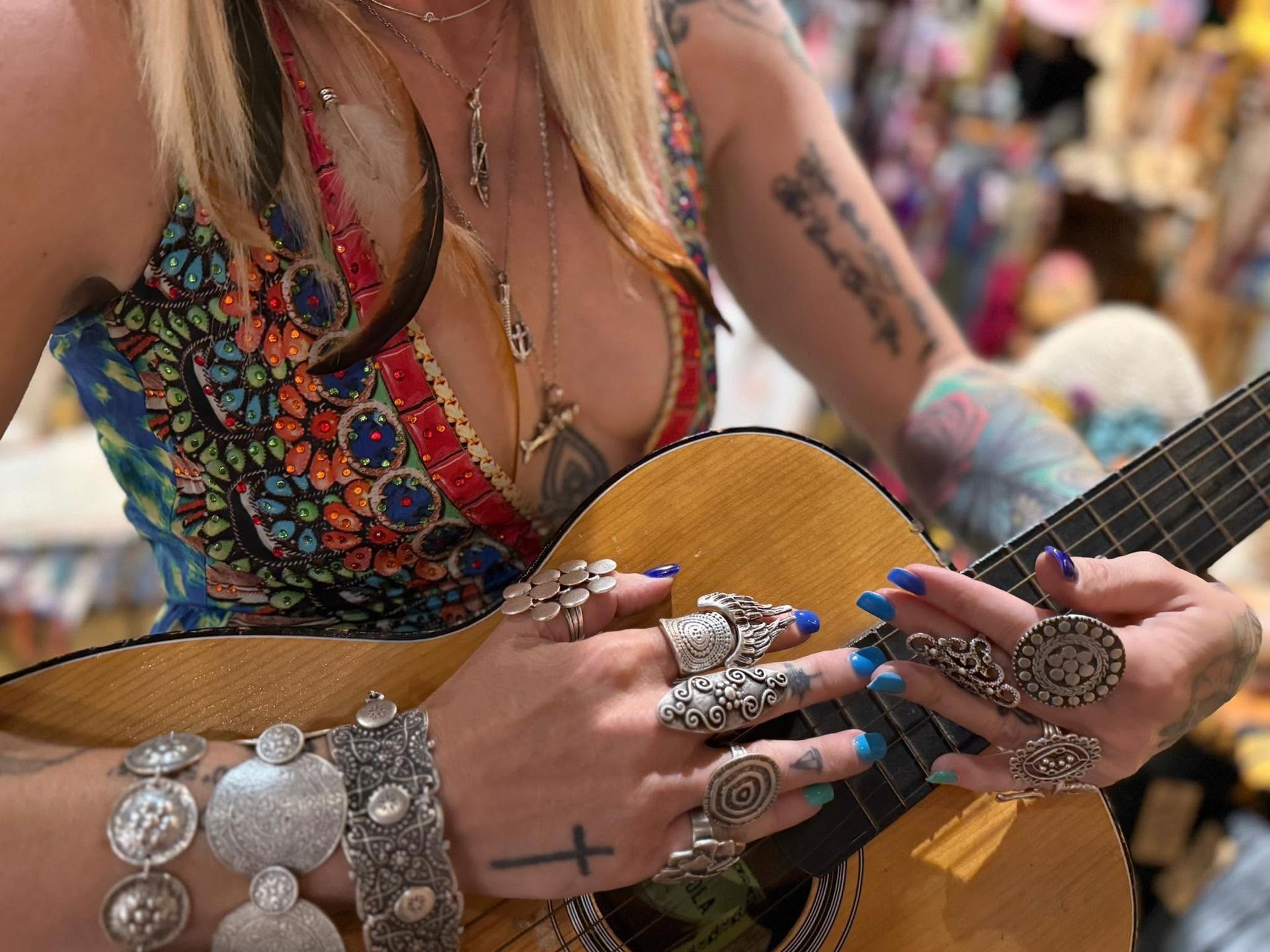 Close-up of a tattooed guitarist strumming an acoustic guitar at an outdoor event
