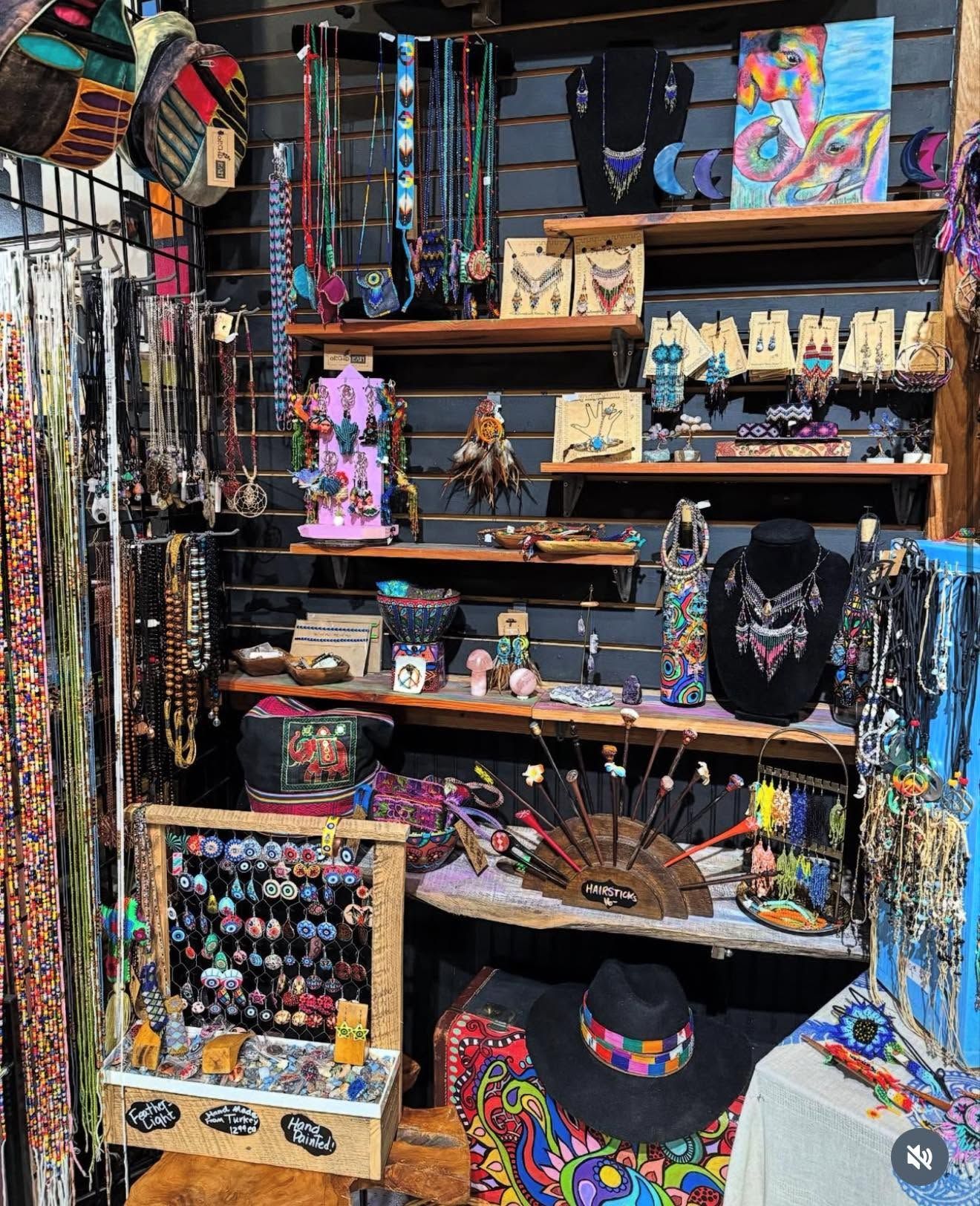 Colorful handmade jewelry and art displayed on shelves in a small craft shop